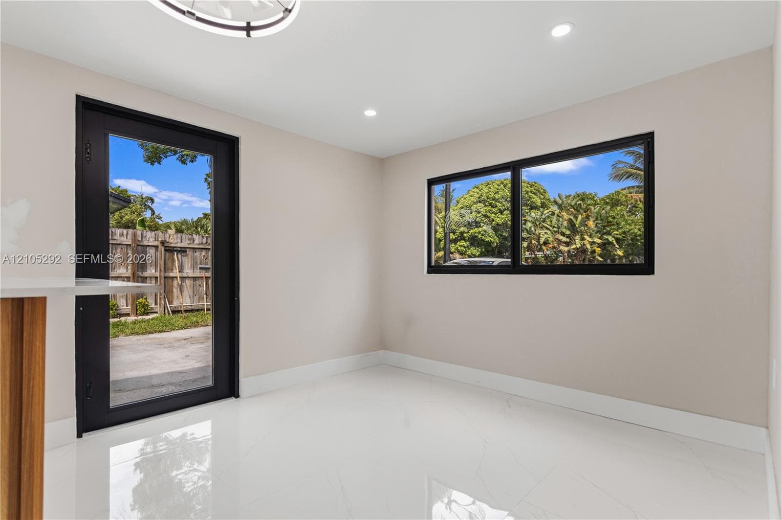 Recessed lighting, wood-finish cabinetry, bright white flooring, black-framed glass door, and black-framed window
