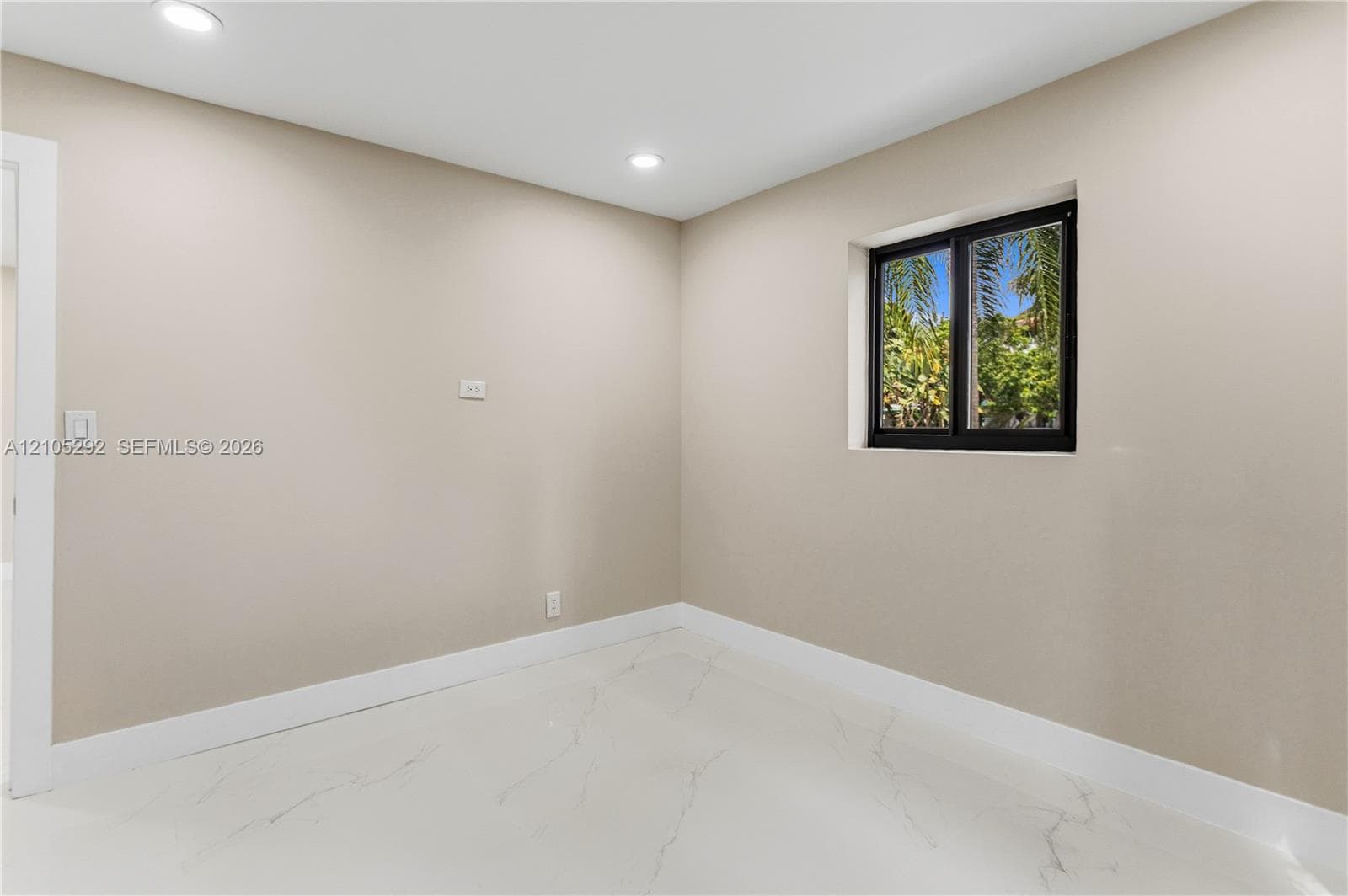 Recessed lighting, light neutral wall paint, white trim, white marble-look flooring, and a black-framed window