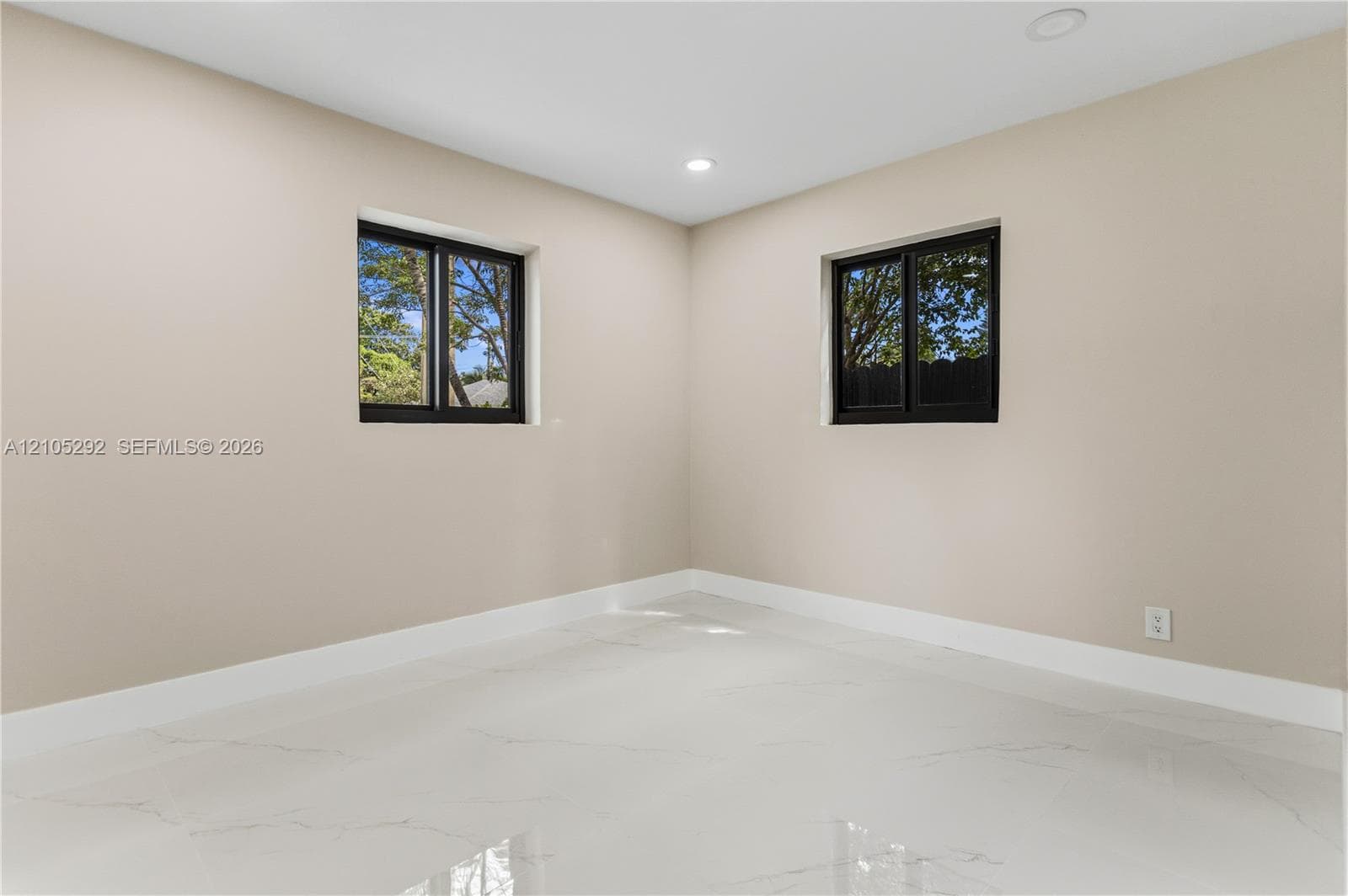 Smooth walls with a neutral finish, recessed lighting, white baseboards, and two windows with black frames