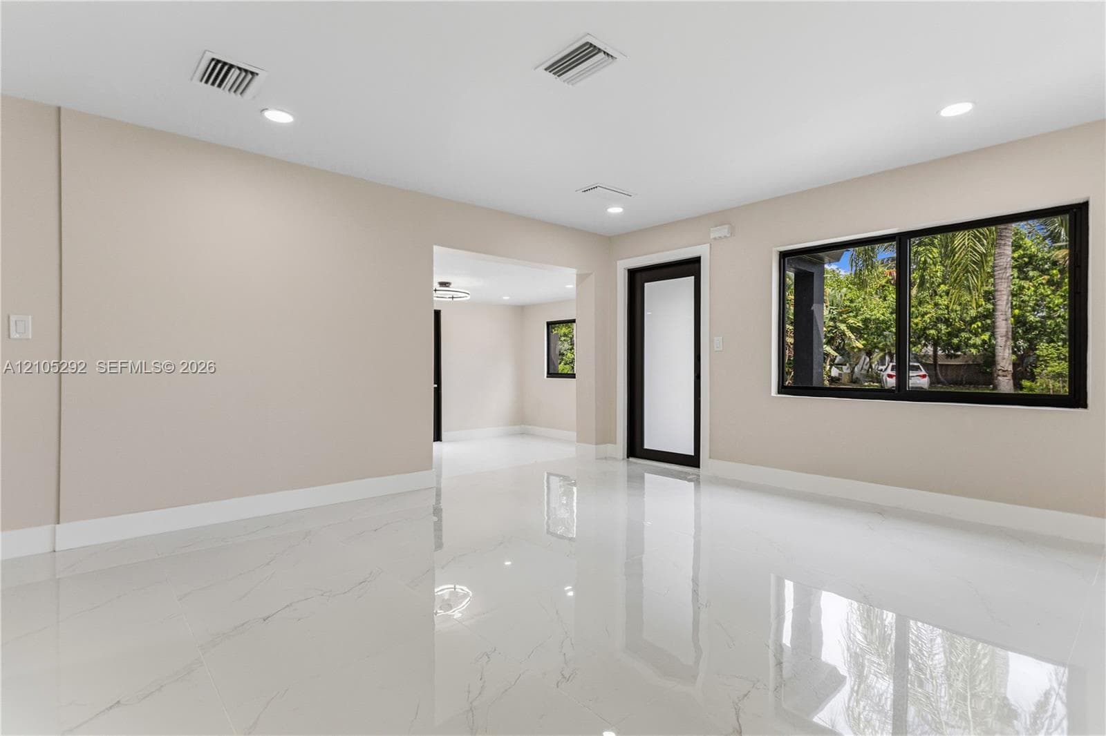 Polished tile flooring, recessed ceiling lighting, light-toned walls, and black-framed windows