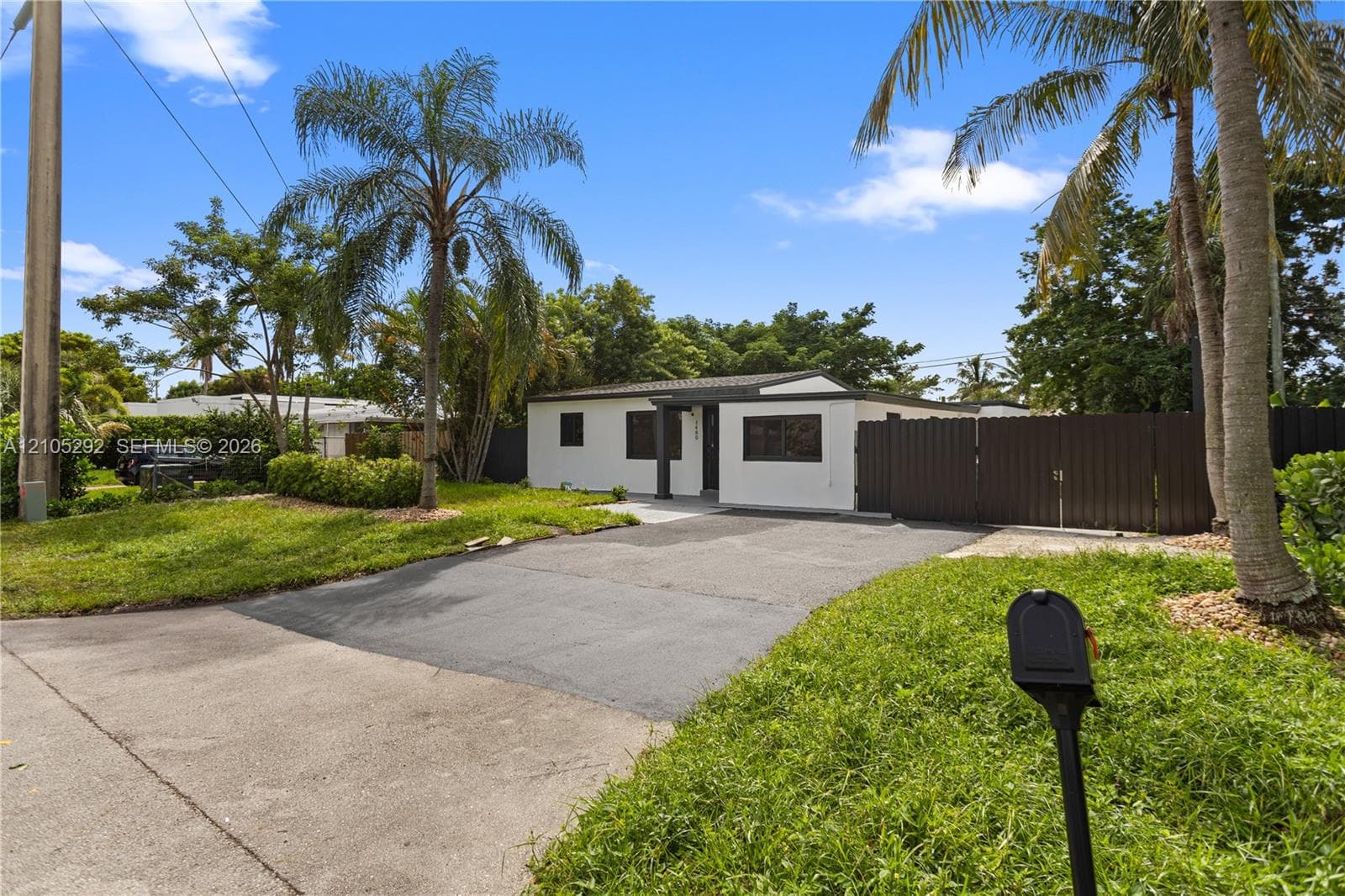 Single-story residence with a paved driveway and dark privacy fencing
