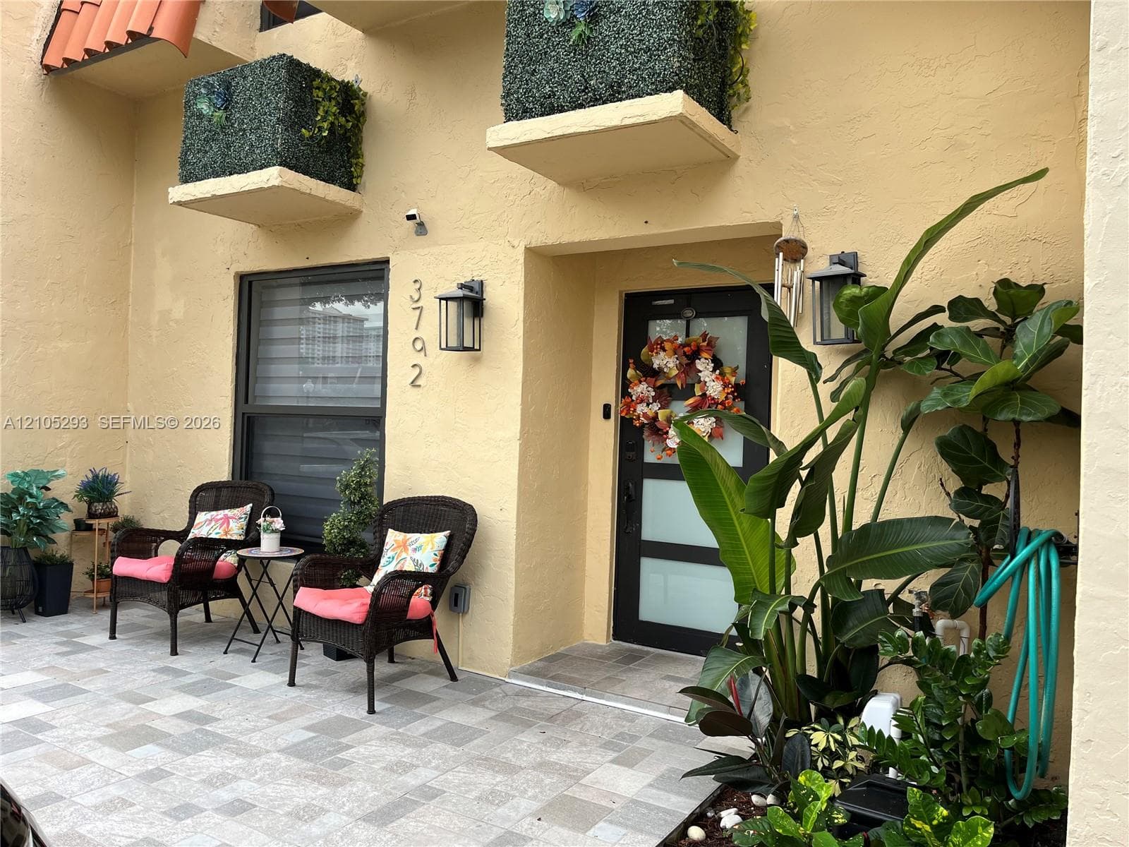Exterior entrance featuring a tiled patio, stucco facade, integrated wall-mounted exterior lighting, and a modern entry door with frosted glass panels