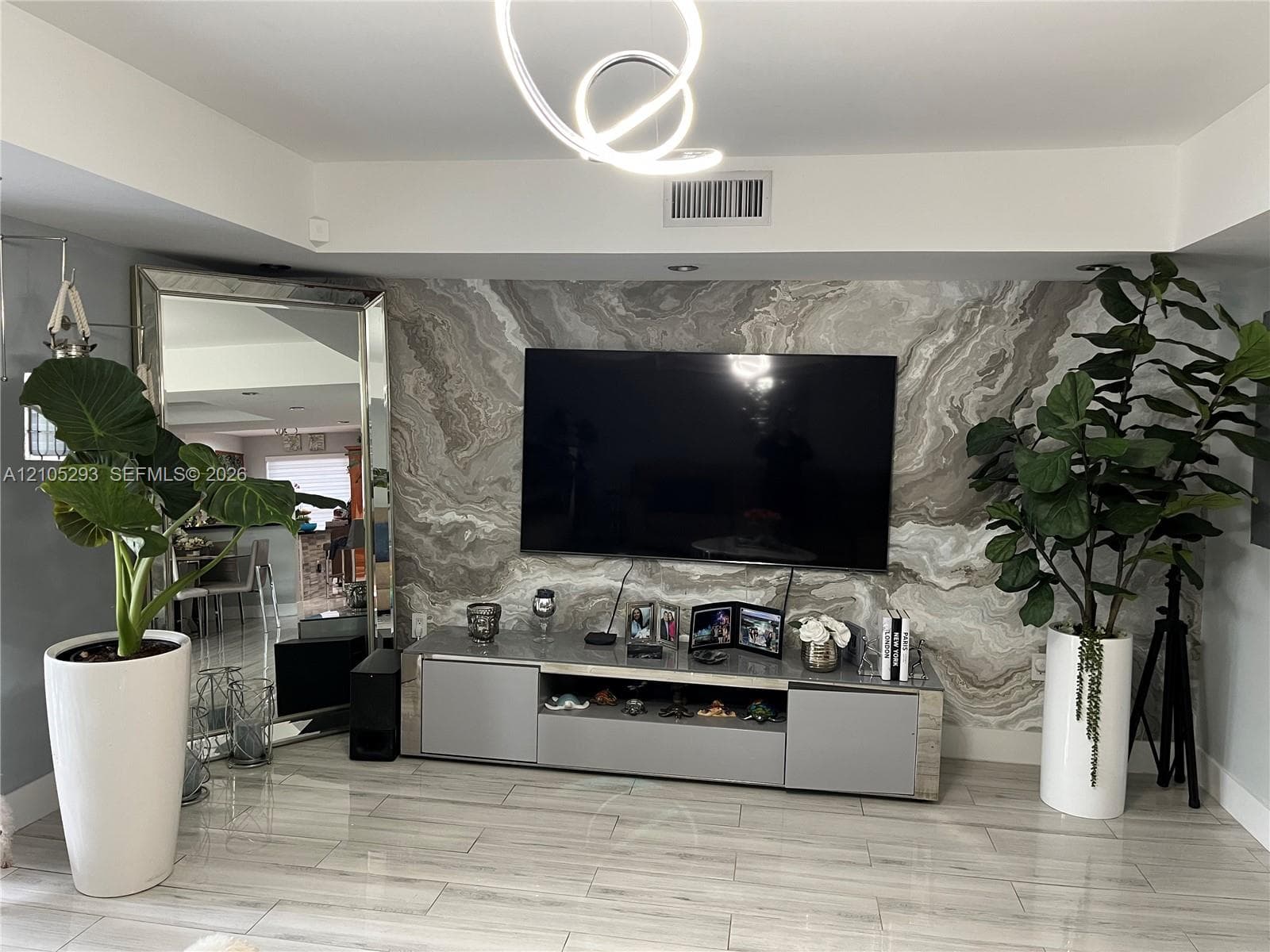 Stone-clad accent wall with organic patterning, light-toned tile flooring, and custom sculptural LED ceiling light fixture