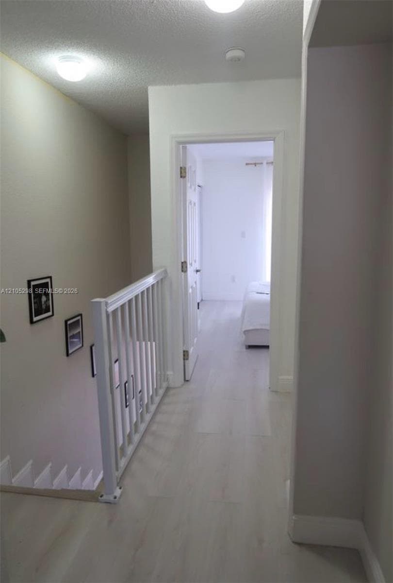 Wood-finish flooring throughout, white baluster railing, flush-mount lighting, and white interior doors
