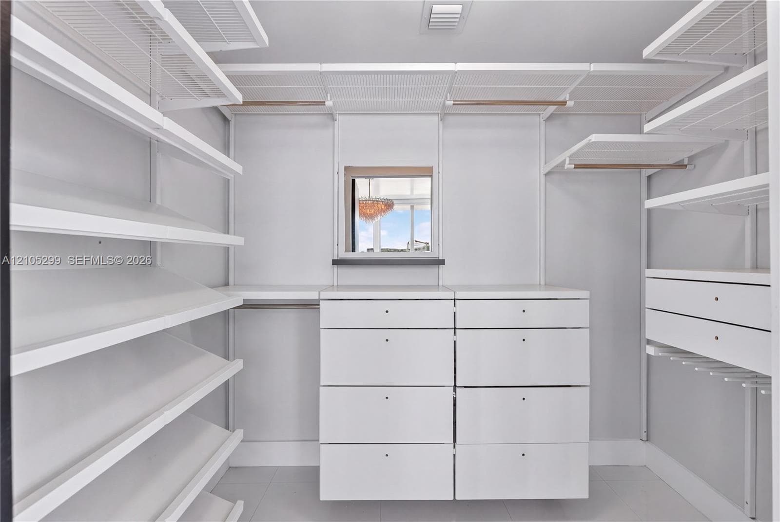 Integrated closet system with extensive shelving, built-in drawer units, hanging rods, and an overhead window