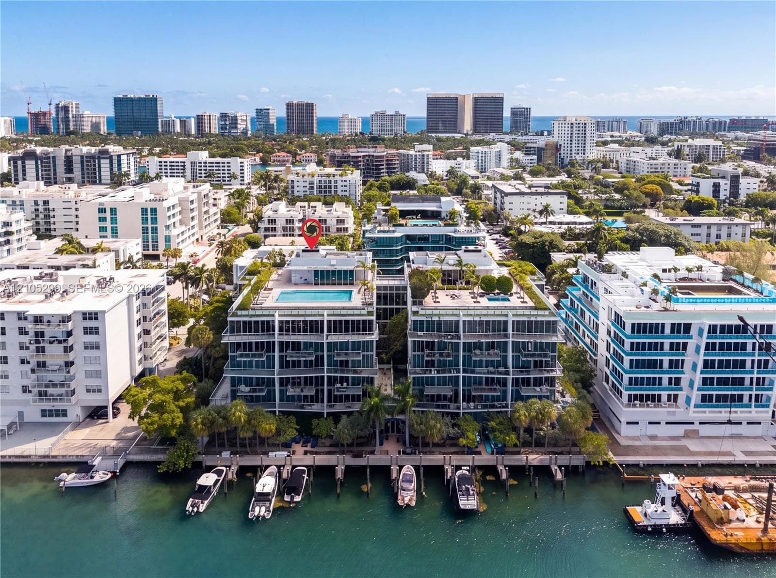 Waterfront residential building with multiple balconies, a rooftop pool, and an adjacent boat dock