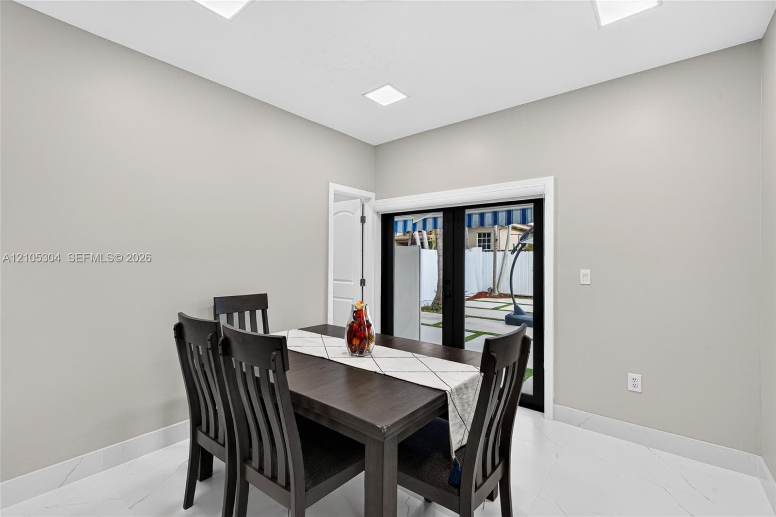 Interior space featuring large-format tile flooring, recessed ceiling lighting, and black-framed French doors with exterior access