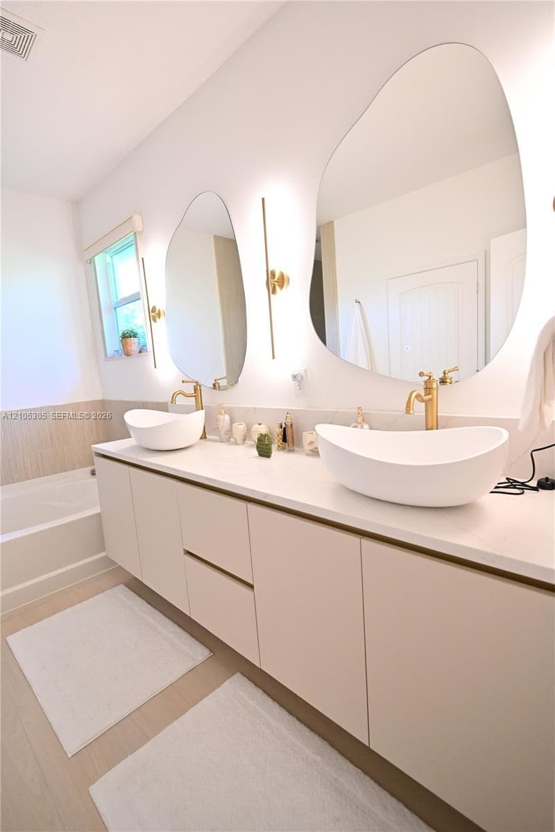 Floating vanity with dual vessel sinks, wall-mounted fixtures, and integrated lighting