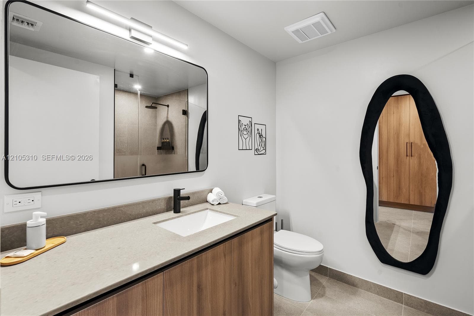 Floating vanity with wood-finish cabinetry, light-toned countertop, and undermount sink
