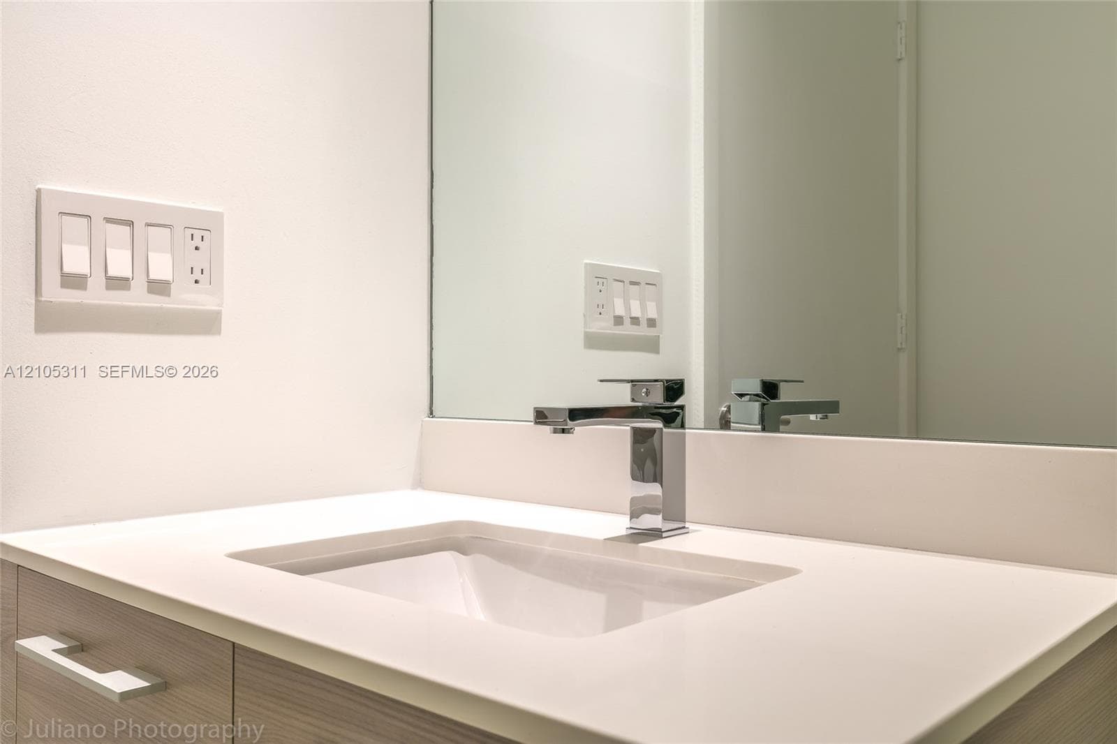 Integrated vanity with an undermount sink, a chrome faucet, and a large wall mirror