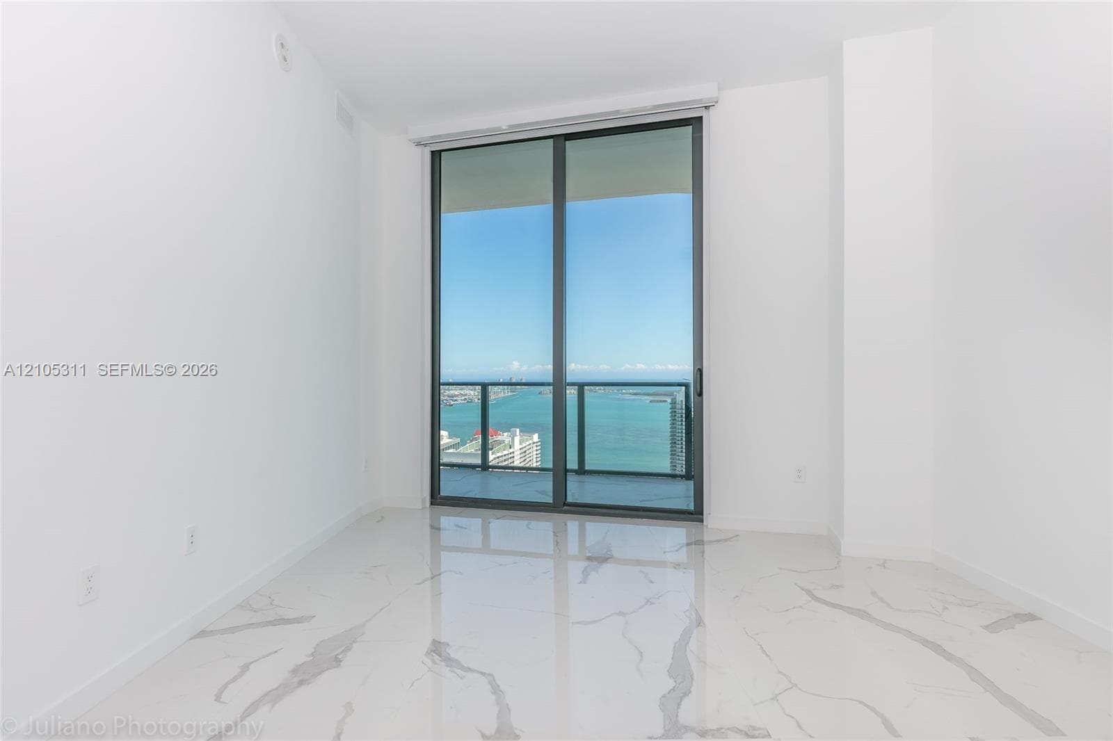 Polished tile flooring, white painted walls, floor-to-ceiling glass doors, and a balcony with metal railings