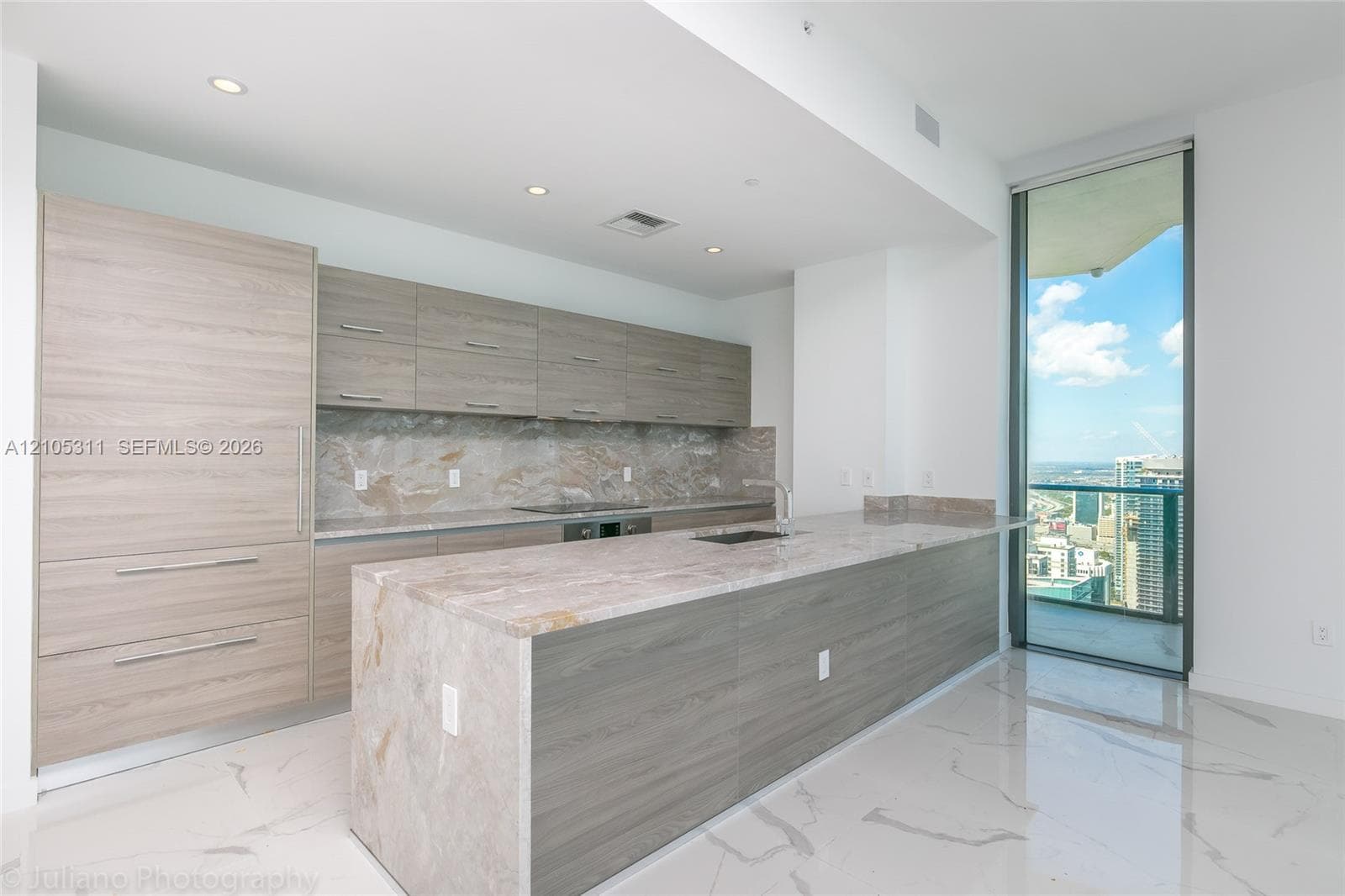 Integrated kitchen featuring full-height panel-front refrigeration, wood-finish cabinetry, and a large central island with an undermount sink