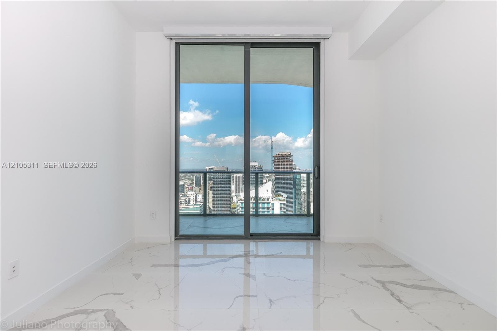 Expansive sliding glass doors, cityscape, balcony, white walls, and marble-finish flooring