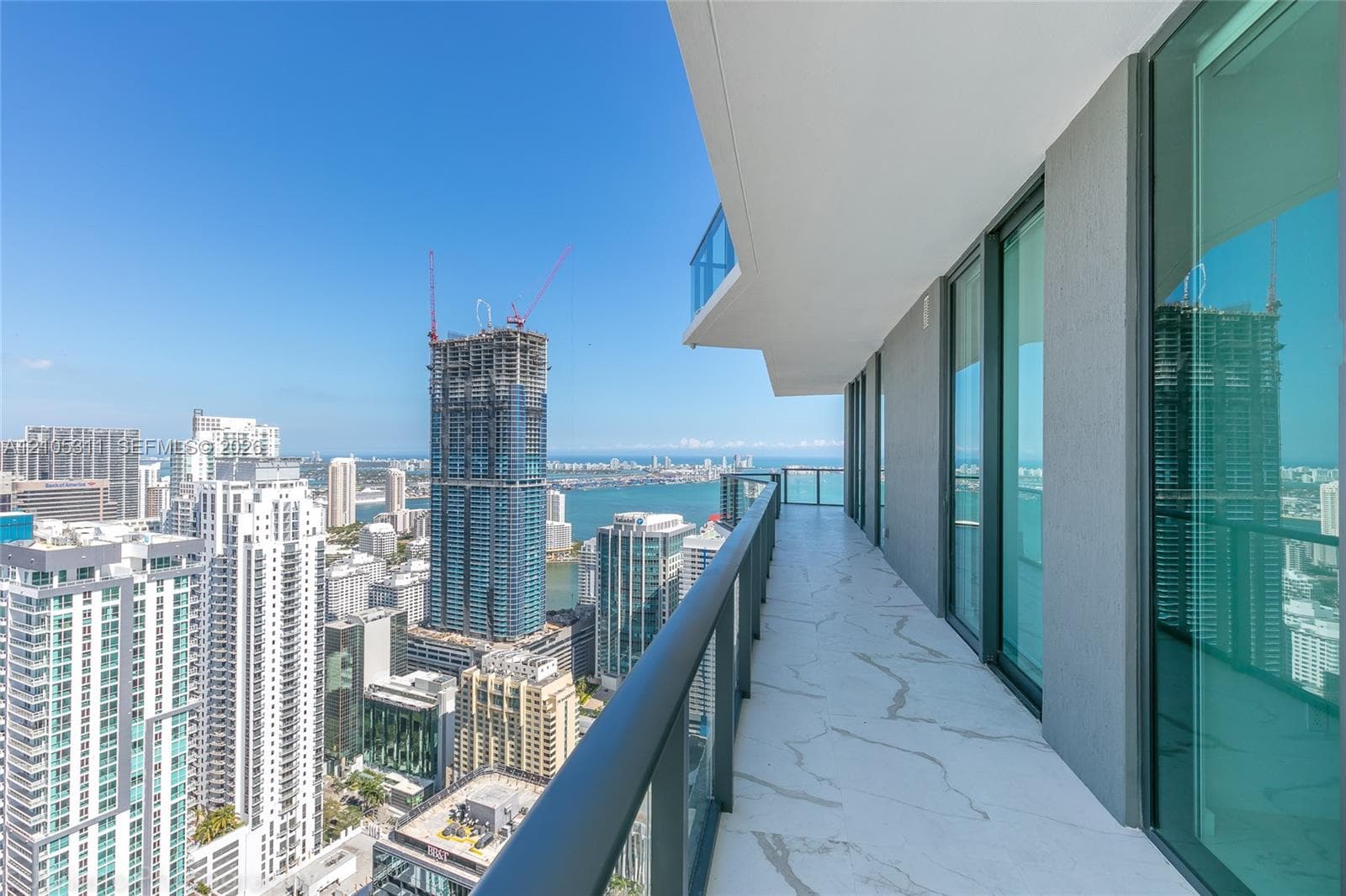 Expansive balcony with marble-look flooring, glass railings, and multiple sliding glass doors