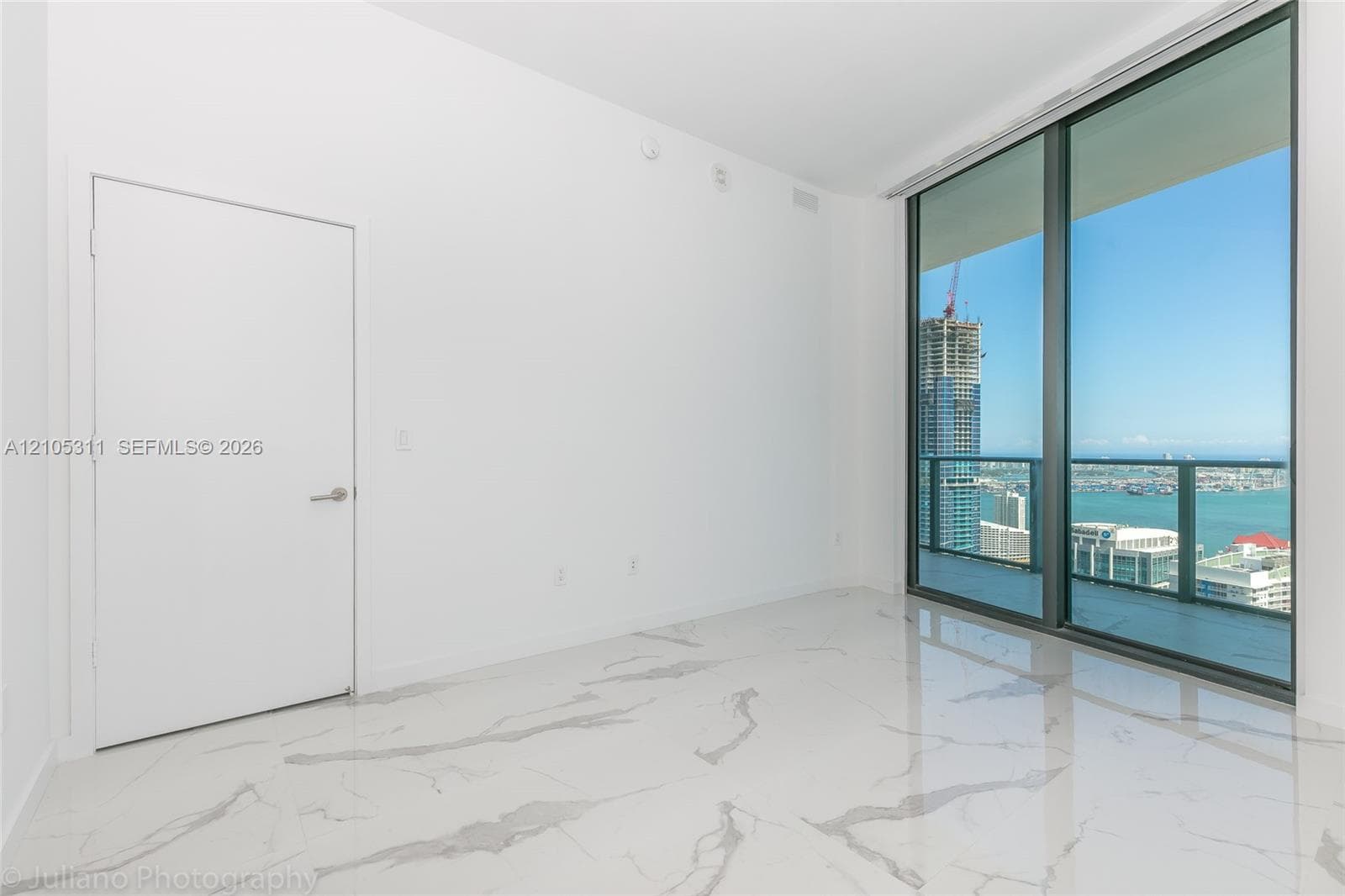Expansive room with large format marble-look flooring and floor-to-ceiling windows