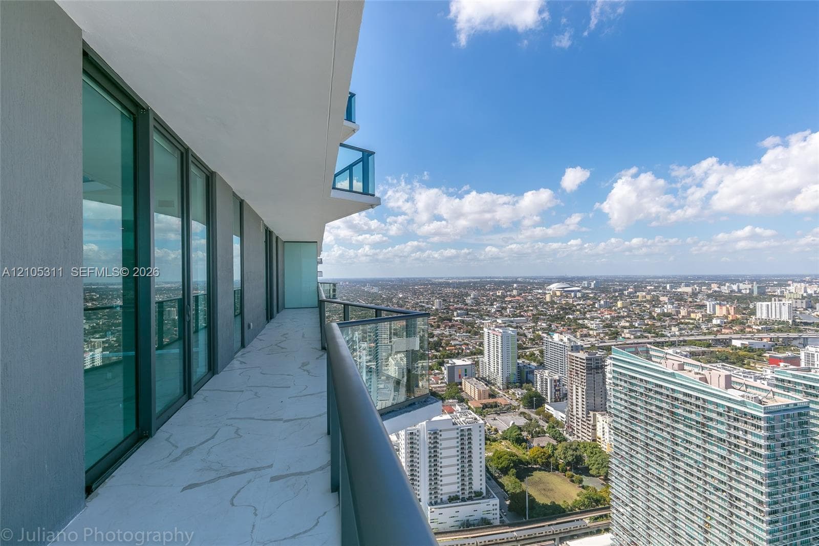Expansive balcony with glass panel railing, featuring a cityscape and distant bodies of water