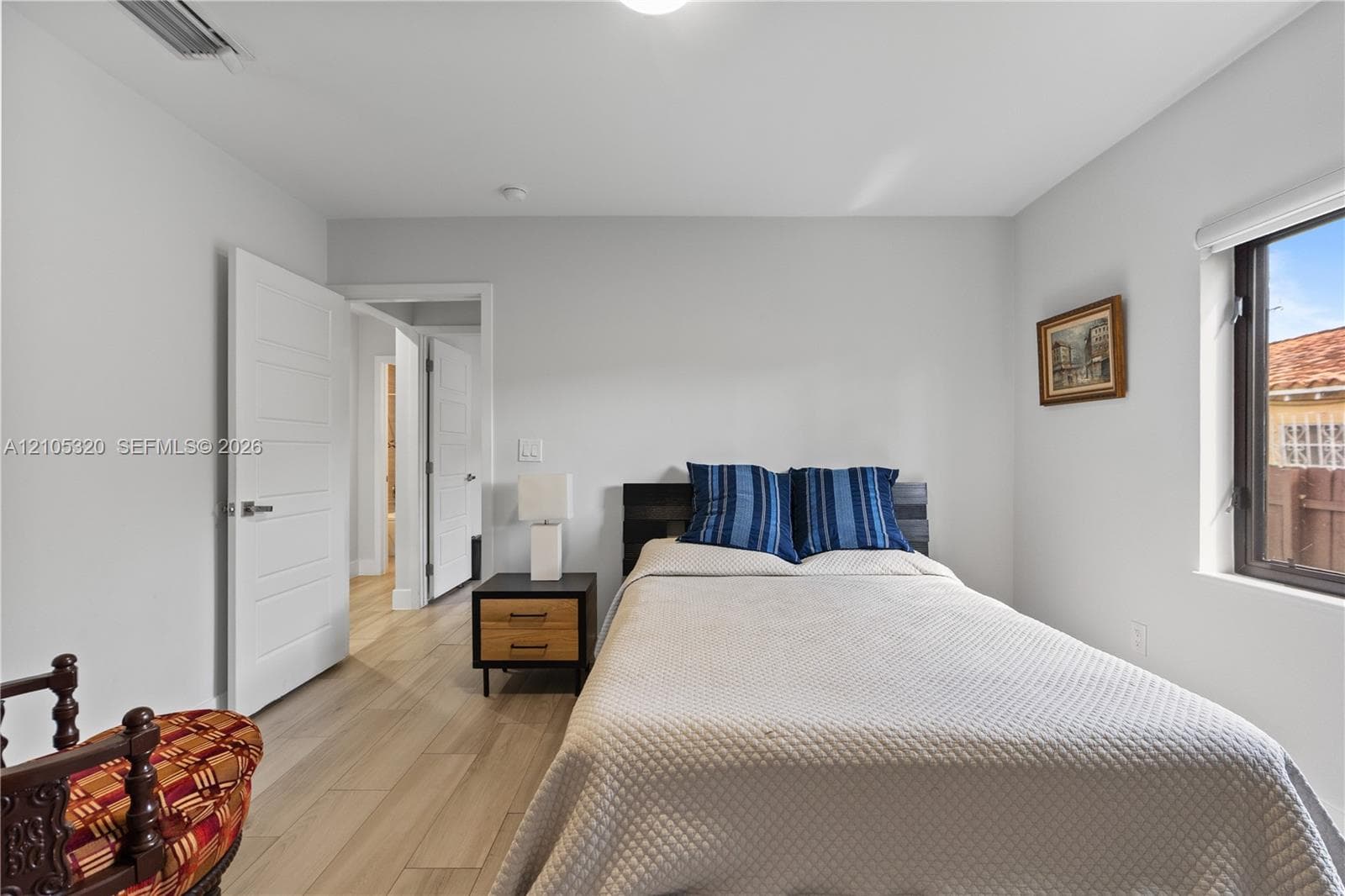 Light wood-finish flooring, white walls, modern white interior doors with horizontal paneling, and a window with blinds