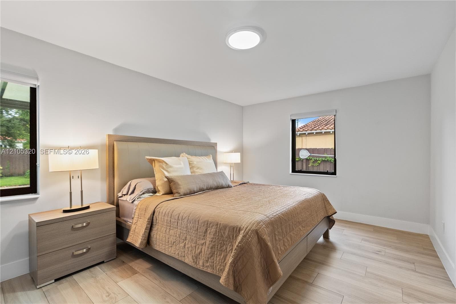 Light wood-finish flooring, recessed ceiling light, and multiple windows with dark frames
