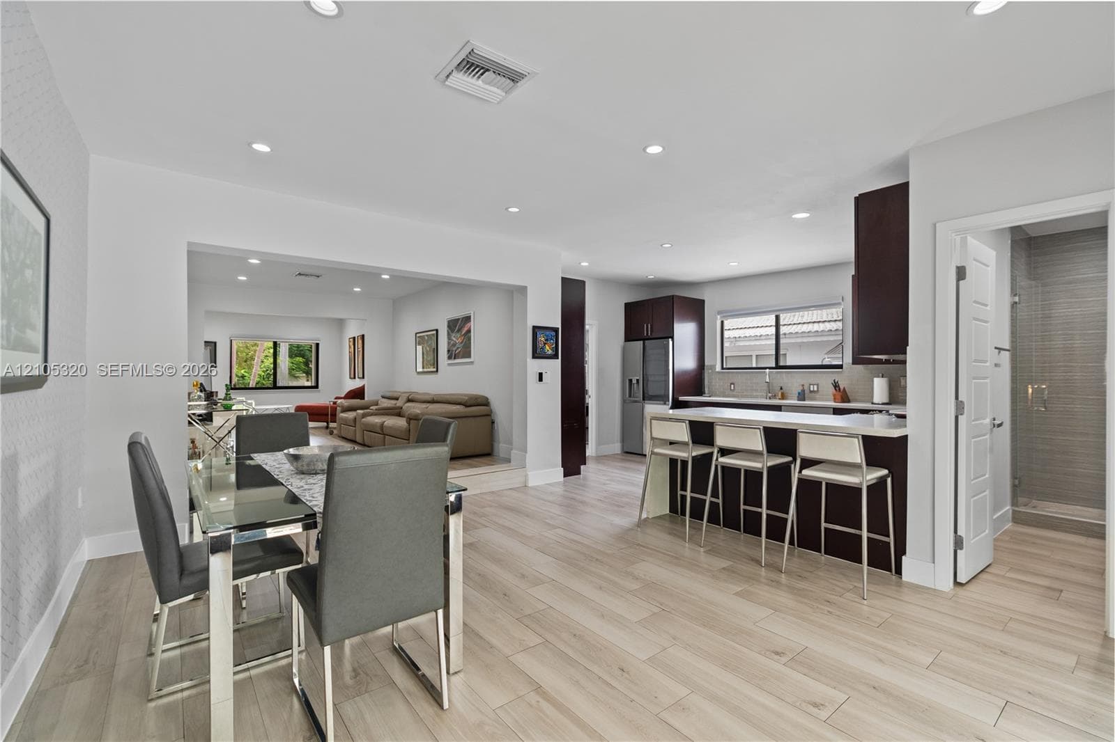 Light wood-finish flooring, recessed lighting, and a kitchen island with seating