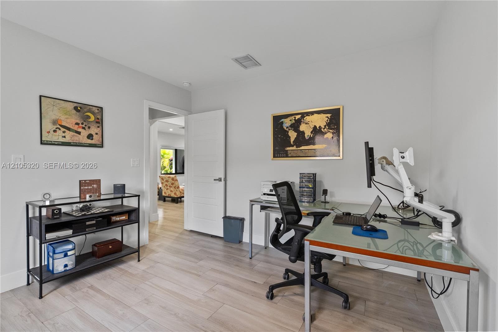 Light-toned wood-finish flooring, white walls, recessed ceiling lighting, and a modern interior door