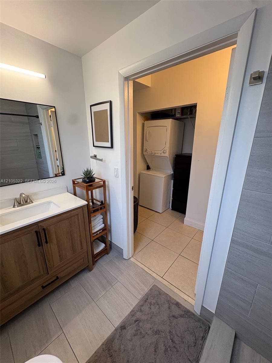 Bathroom featuring a wood-finish vanity with an integrated sink, a rectangular mirror, and gray large format tile flooring