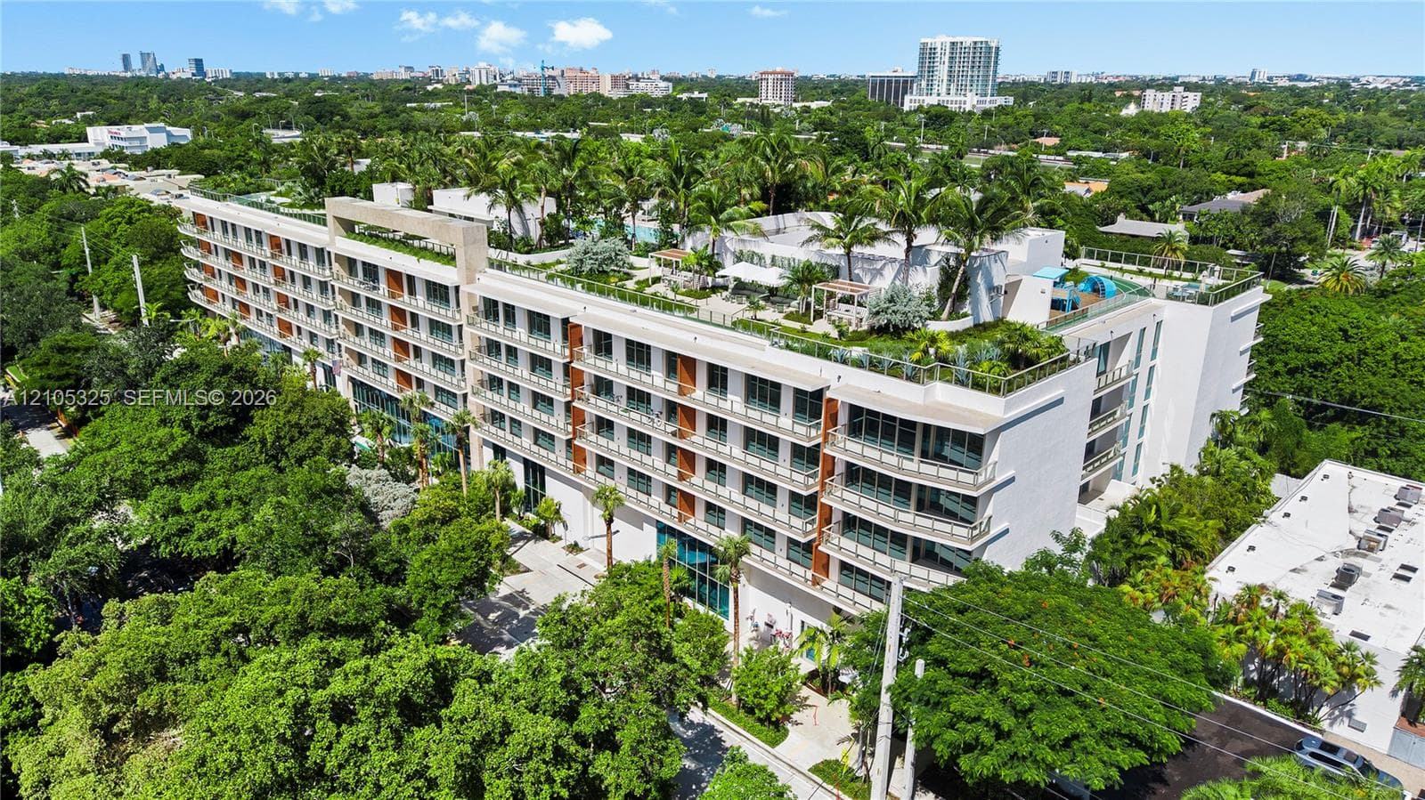 Modern mid-rise building with multiple balconies, a rooftop terrace, and a rooftop pool
