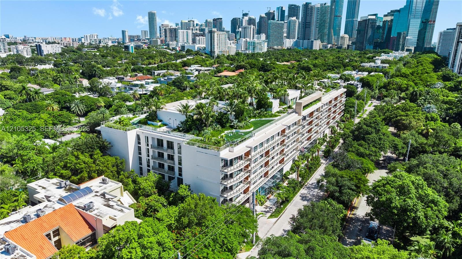 Modern multi-story building featuring extensive rooftop landscaping and multiple private balconies