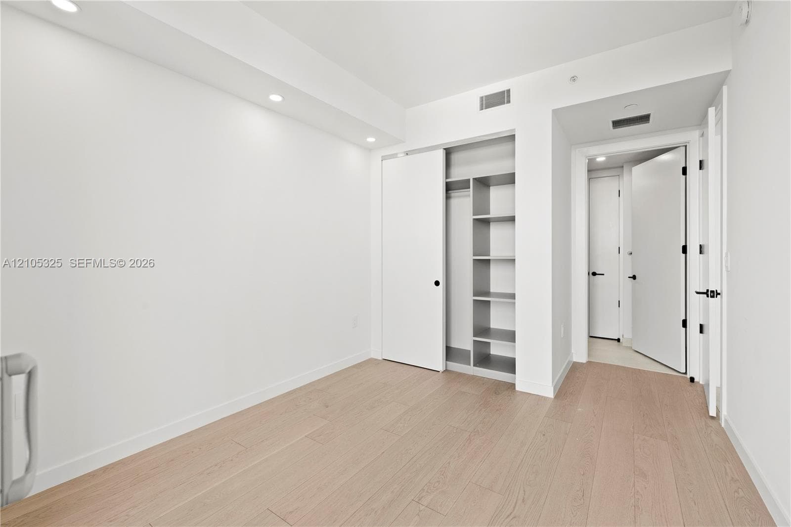 Recessed lighting, wood-finish flooring, built-in closet shelving, and modern doors with dark hardware