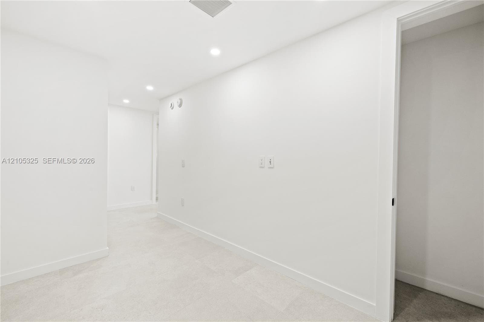 Recessed lighting, light-toned carpeting, white wall finishes, crisp white trim, and a doorway