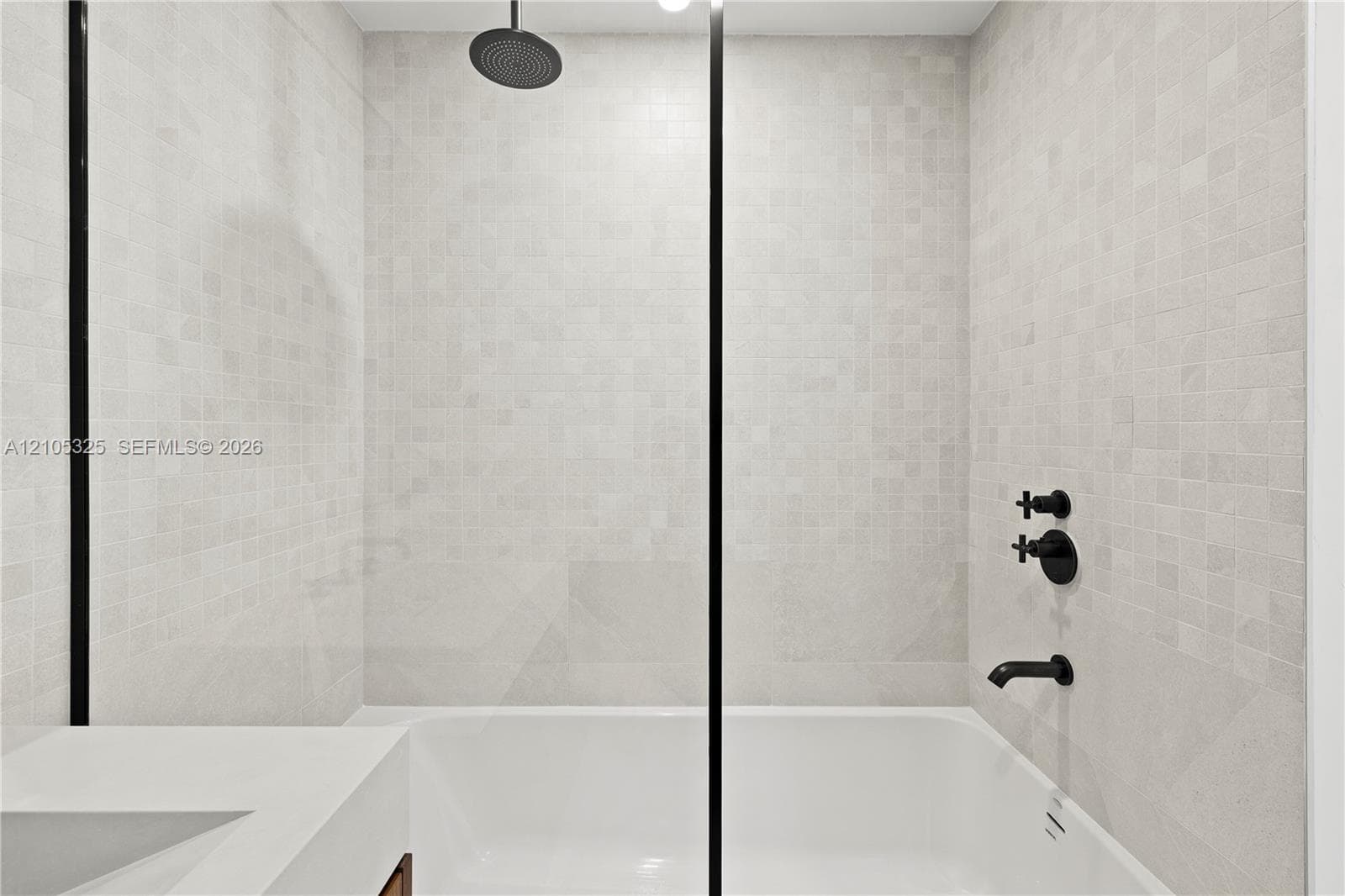 Shower-over-tub combination with black matte fixtures and a rainfall showerhead
