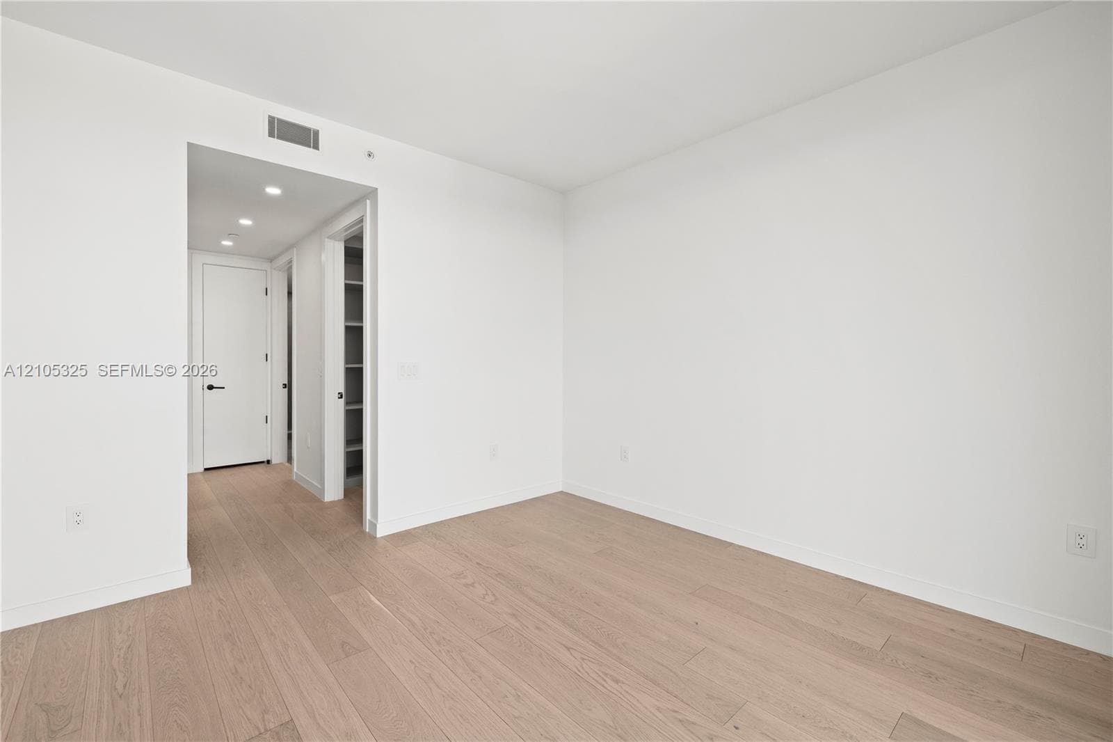 Recessed lighting, wood-finish flooring, white walls, built-in shelving, and flush-panel doors