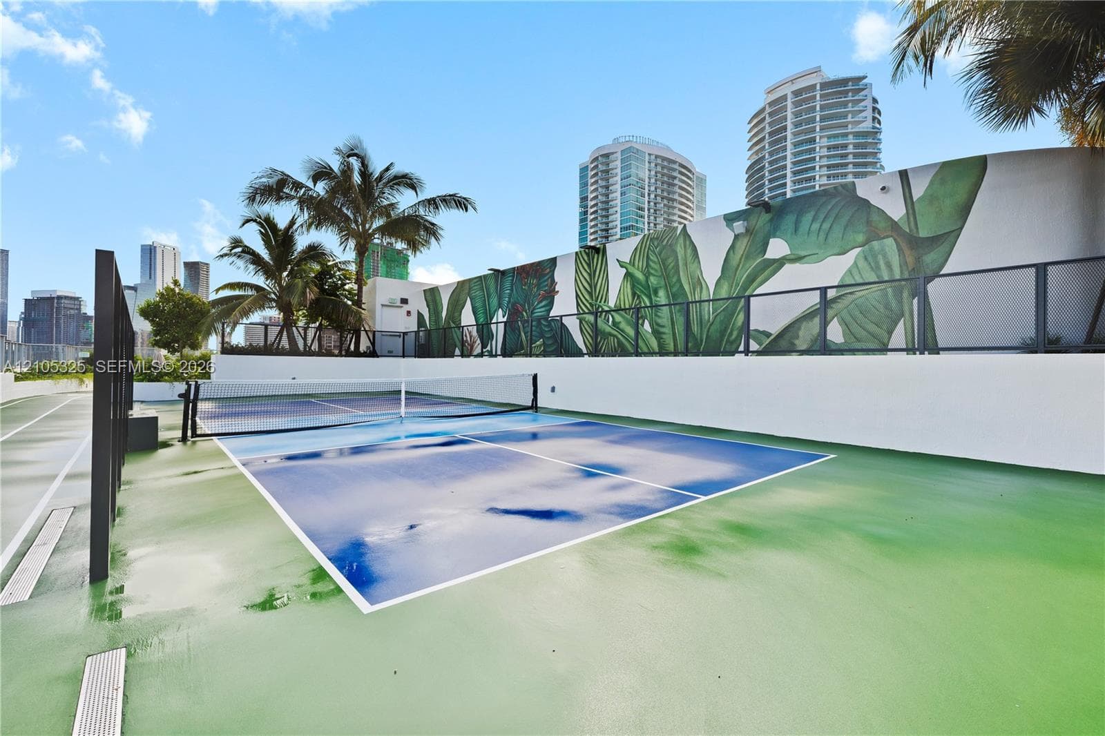 Multi-sport court featuring a blue playing surface and green surrounding area