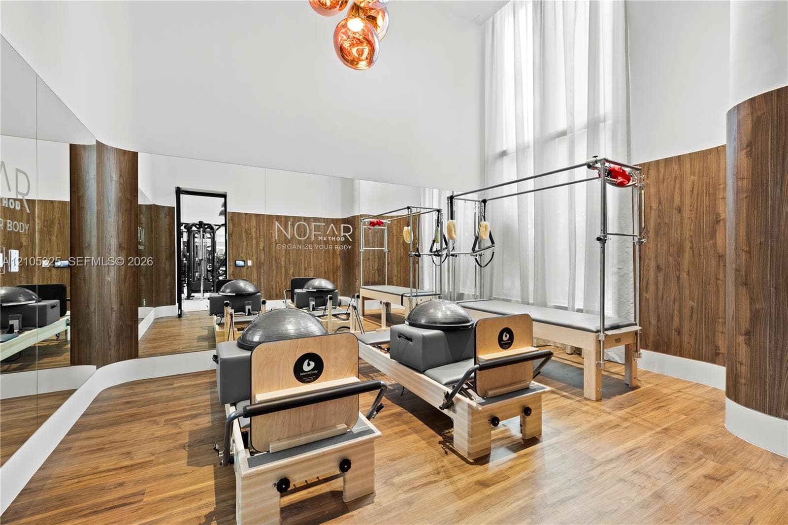 Fitness studio featuring wood-finish flooring, mirrored walls, and warm-toned wood paneling