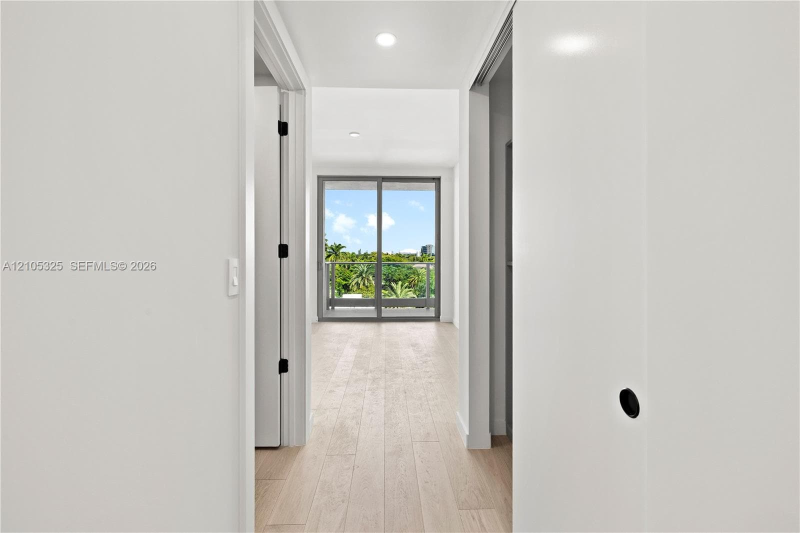Light wood-finish flooring extending into the distance, with crisp white walls and recessed lighting