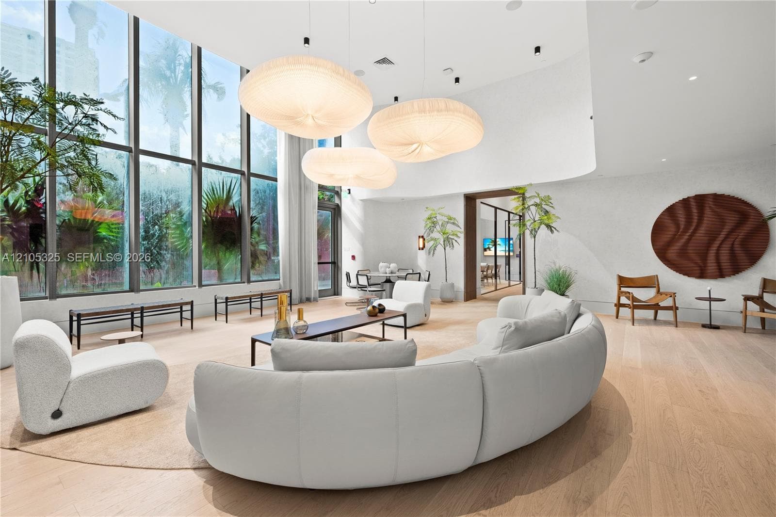 Expansive floor-to-ceiling windows, light wood-finish flooring, custom curved walls, recessed lighting, and unique pendant light fixtures