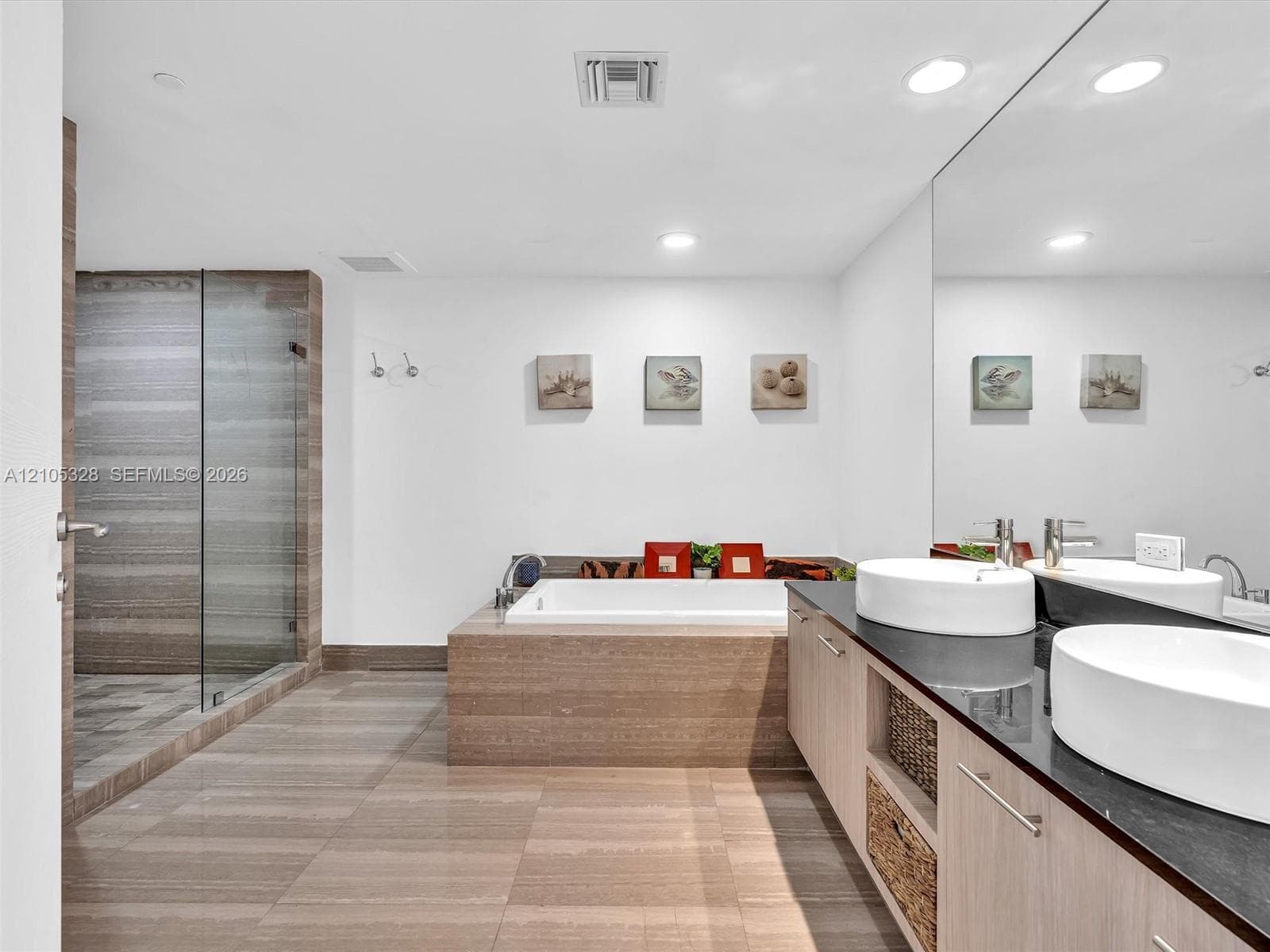 Luxurious spa-inspired bathroom featuring dual vessel sinks, an expansive vanity with built-in storage, a full-width mirror, a soaking tub, and a separate glass-enclosed shower.