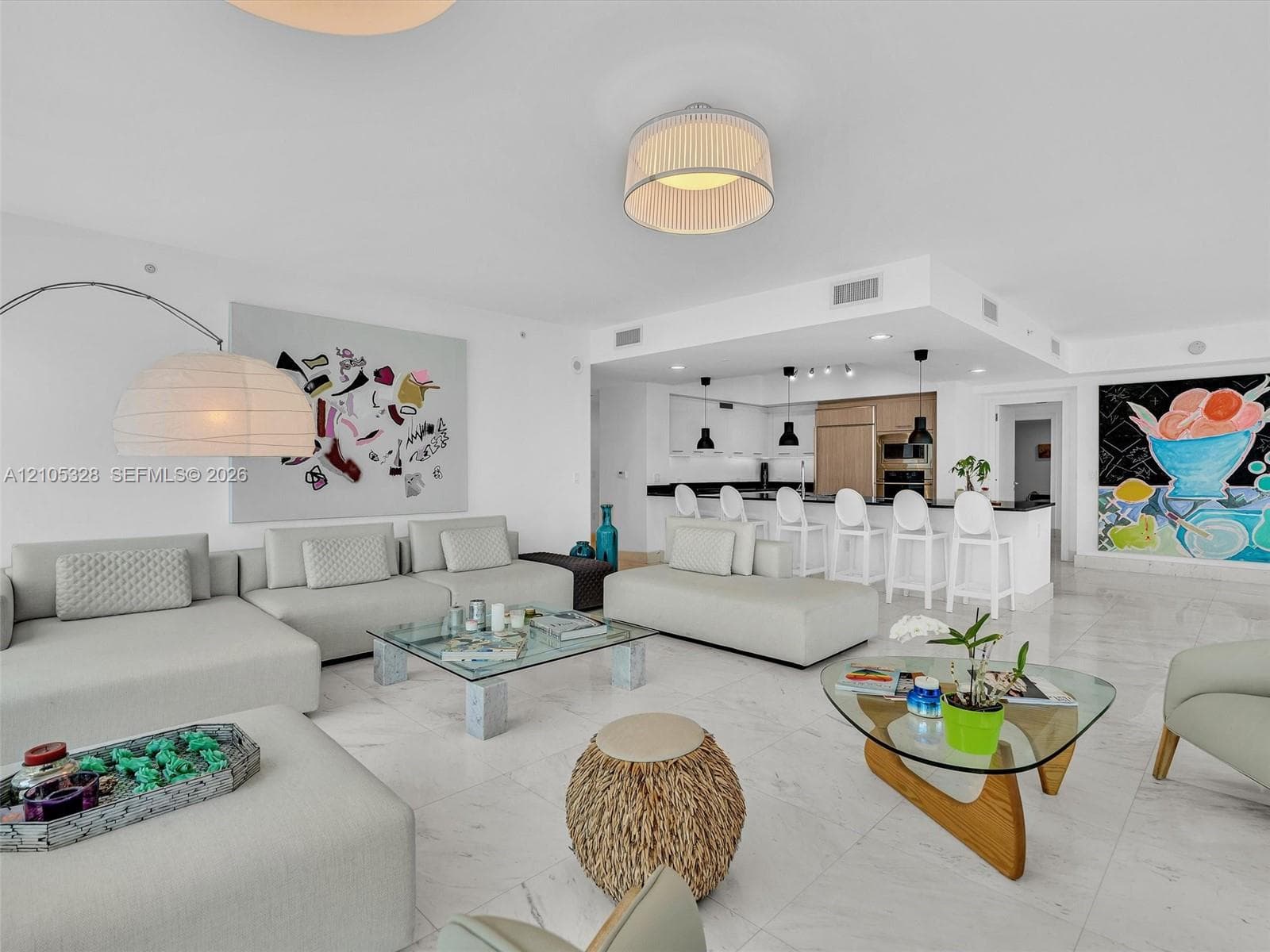 Spacious open-concept living area featuring Carrara marble flooring and recessed ceiling lighting.