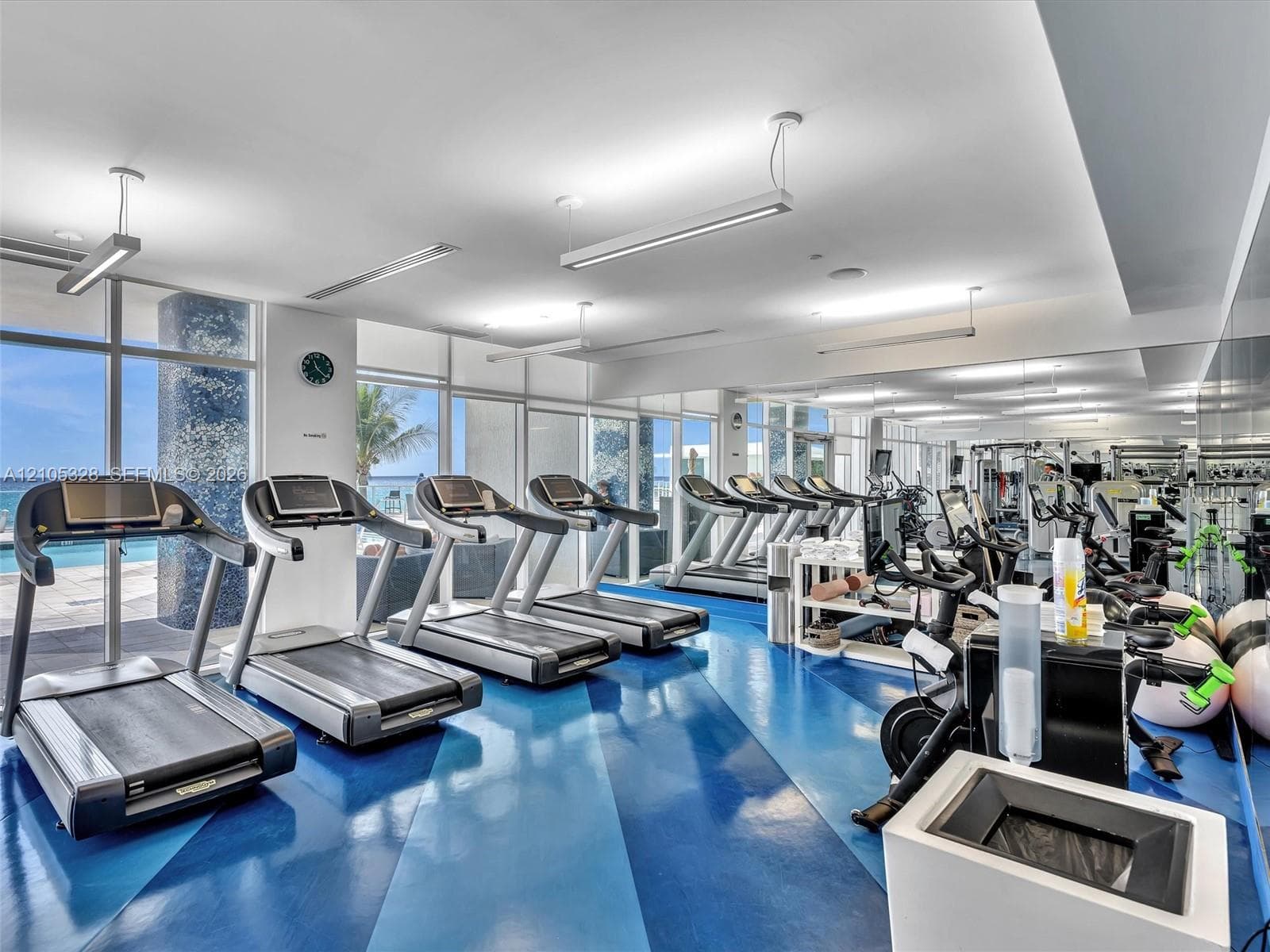 Expansive fitness center featuring a blue and dark blue patterned floor, floor-to-ceiling windows, and abundant natural light