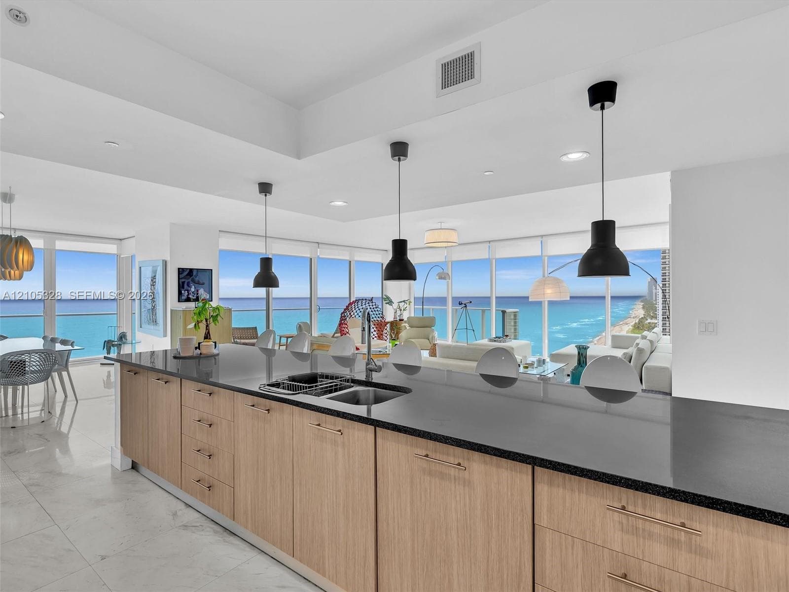 Modern kitchen featuring a spacious center island with a double sink, sleek black countertops, and elegant wood-finish cabinetry.