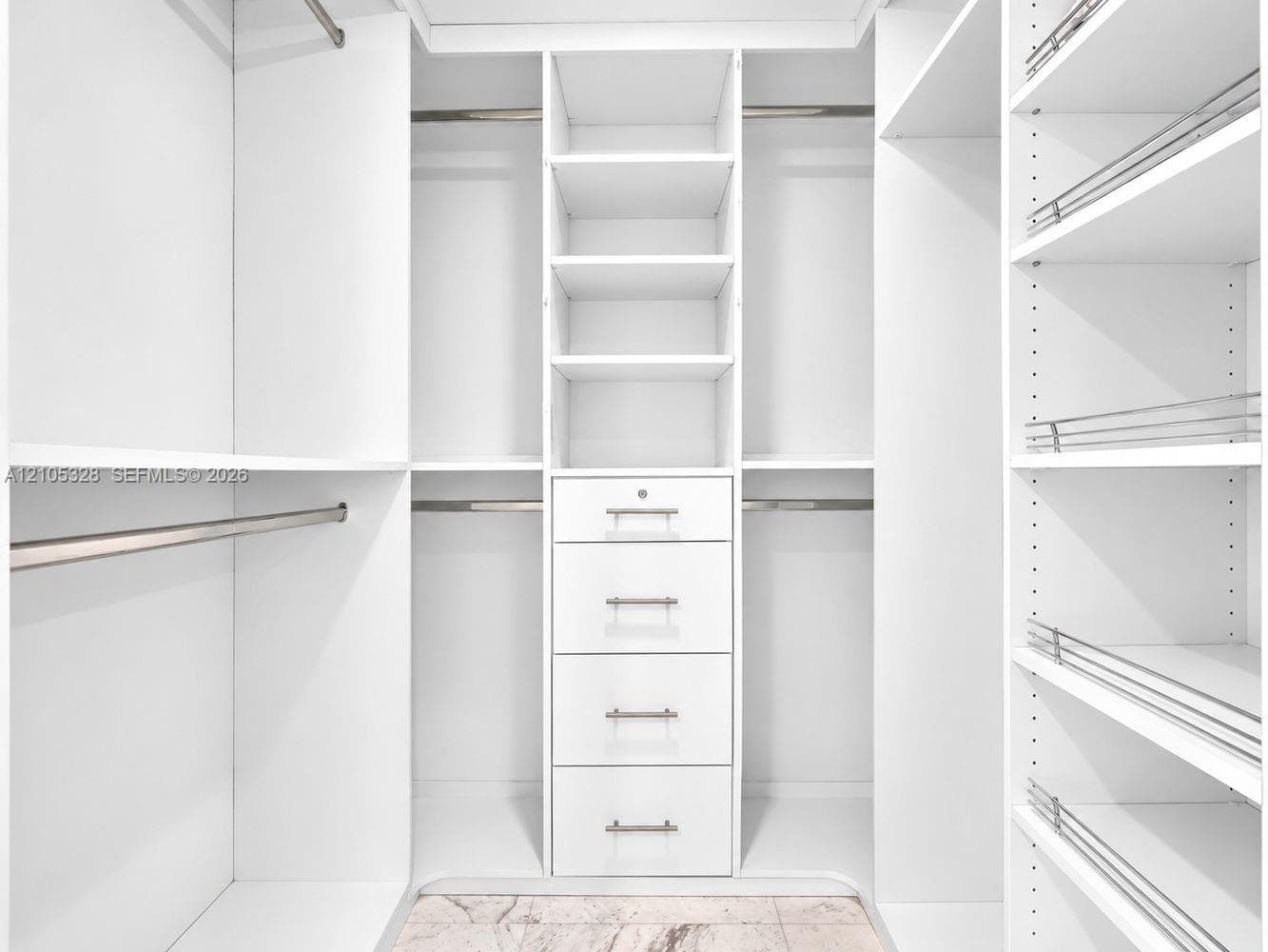 Custom-designed closet featuring ample hanging space, built-in shelving, and a five-drawer storage unit with brushed nickel hardware.