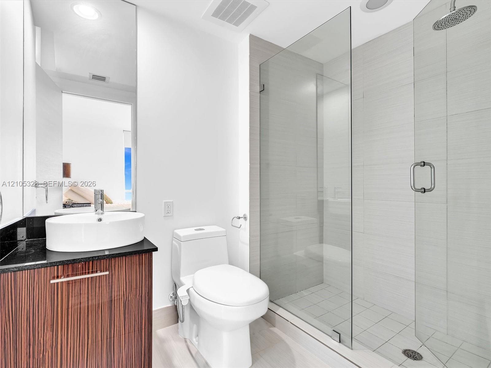 Elegant contemporary bathroom featuring a sleek vanity with warm finish cabinetry and a sophisticated dark countertop.