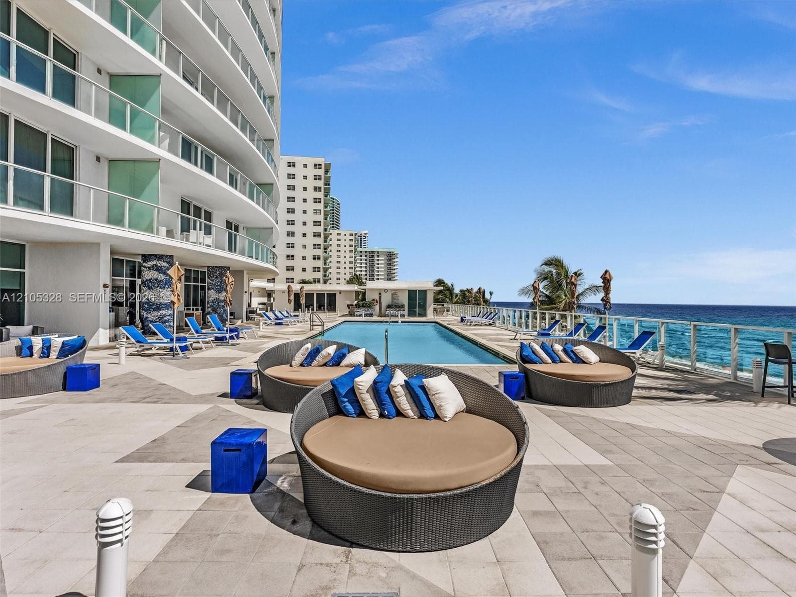 Experience oceanfront resort-style living at Apogee Beach, featuring an inviting swimming pool, expansive pool deck, sleek glass railings, and direct access to the beach and Atlantic Ocean.