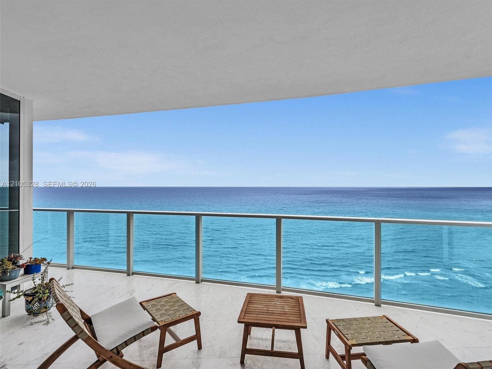 Expansive private balcony featuring glass railings and breathtaking, unobstructed panoramic ocean views.