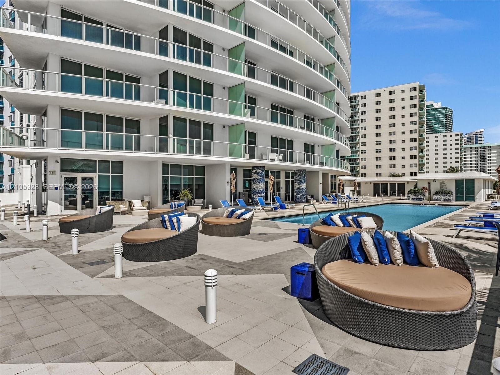 Experience oceanfront resort-style living at Apogee Beach, featuring an inviting swimming pool, expansive pool deck, sleek glass railings, and direct access to the beach and Atlantic Ocean.