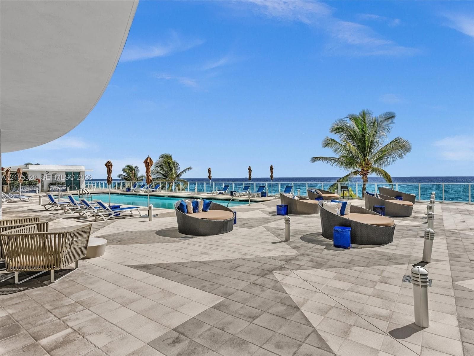 Experience oceanfront resort-style living at Apogee Beach, featuring an inviting swimming pool, expansive pool deck, sleek glass railings, and direct access to the beach and Atlantic Ocean.