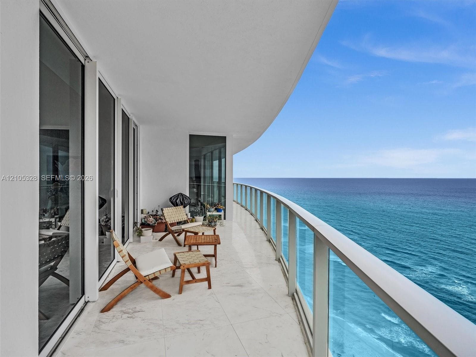 Expansive curved balcony with glass railings and panoramic ocean views.