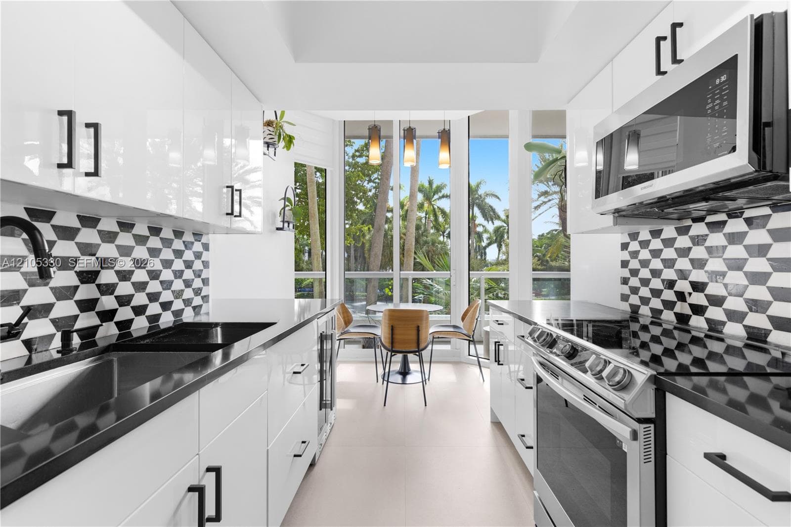Contemporary kitchen featuring white high-gloss cabinetry, black hardware, black countertops, and a striking geometric tile backsplash