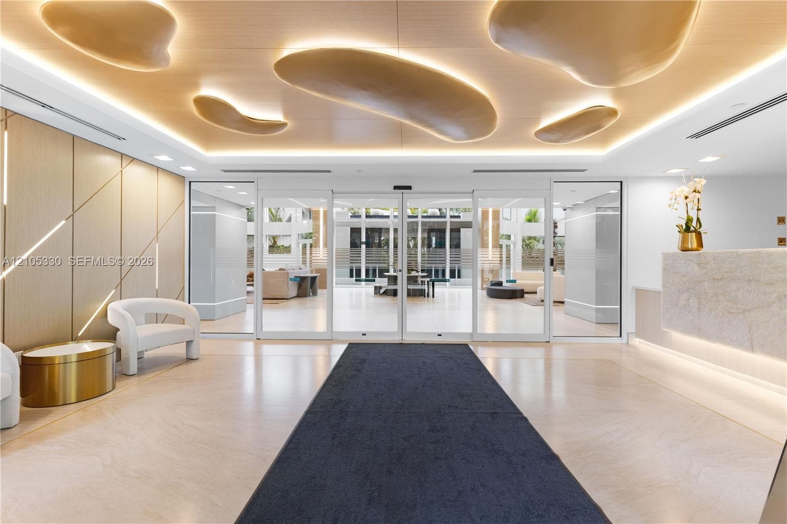 Lobby featuring a stone reception desk, wood-panel accent wall, recessed ceiling lighting, and large glass entry doors
