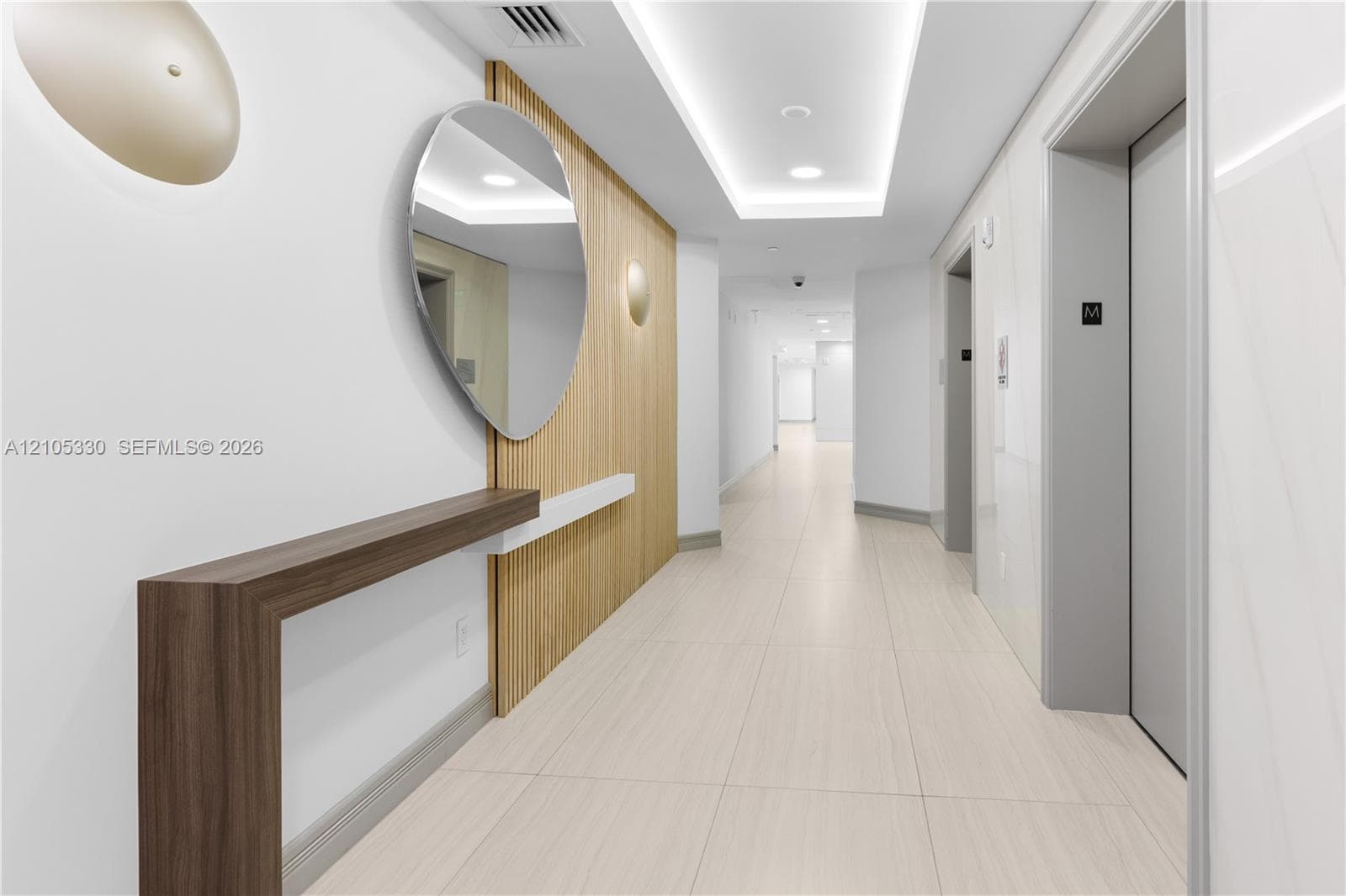 Hallway with wood-finish paneling, contemporary wall sconces, wood-finish console table, and recessed ceiling lighting