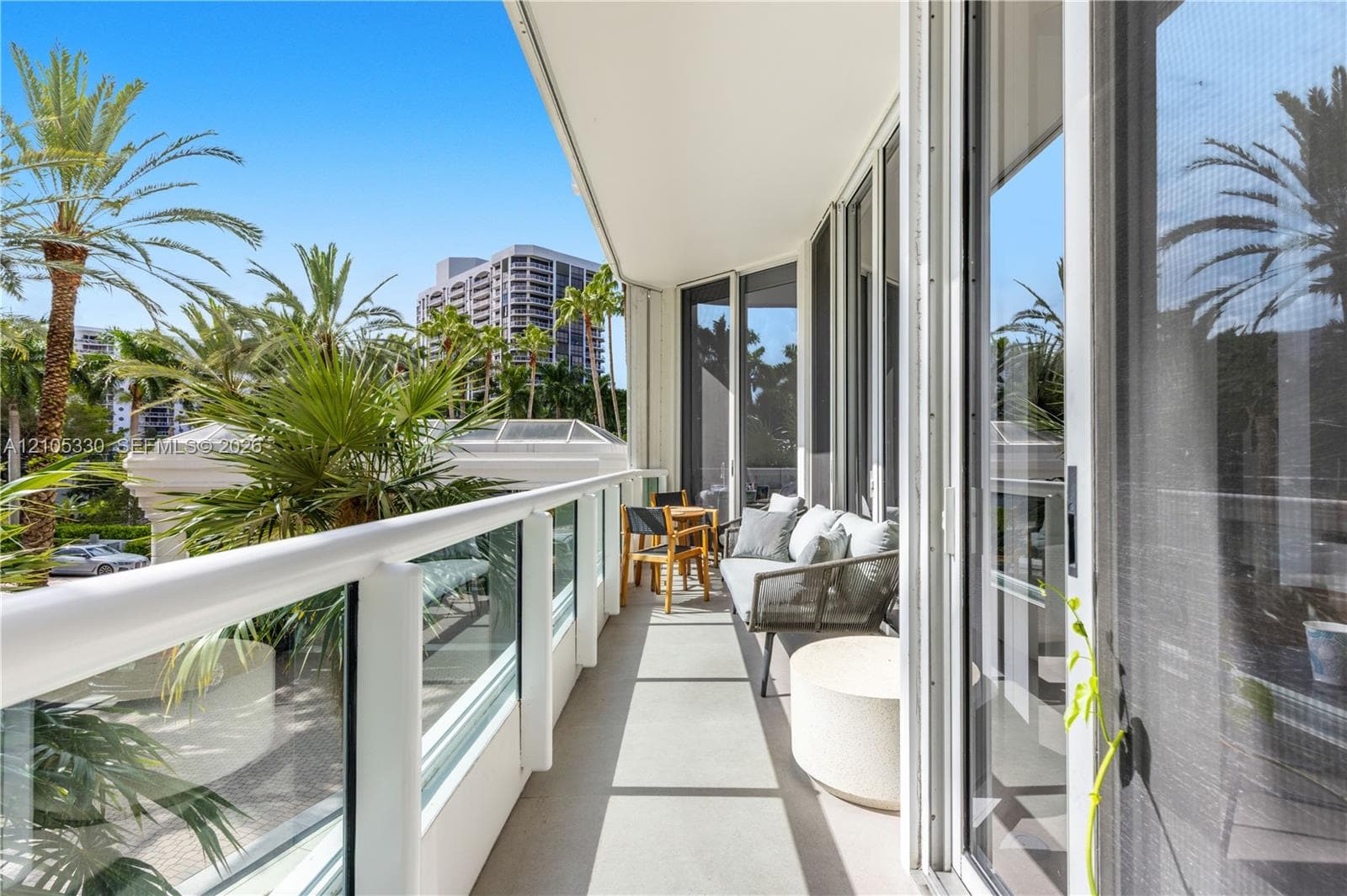 Expansive balcony featuring a glass and white railing, concrete flooring, and full-height sliding glass doors